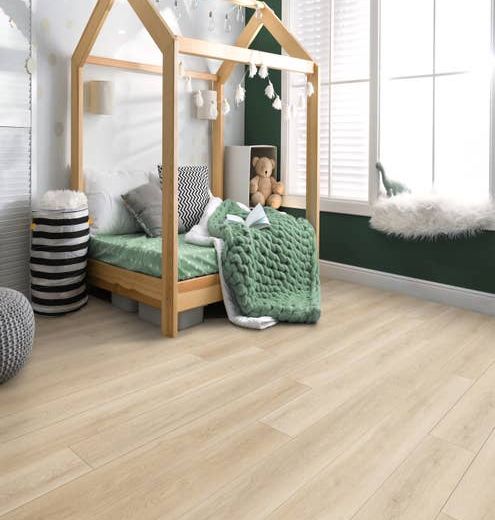 Simple clean child's bedroom with various toys and bedding and a dark green feature wall, a large window, and light wood-look LVP flooring.