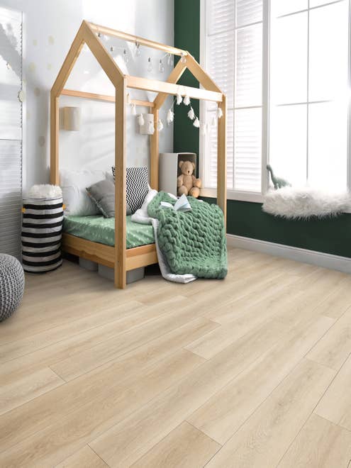 Simple clean child's bedroom with various toys and bedding and a dark green feature wall, a large window, and light wood-look LVP flooring.