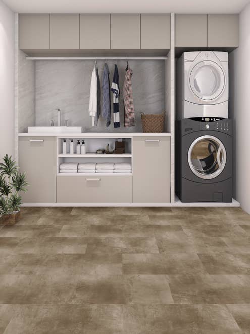 Laundry room with built-in light gray cabinets, stacked white/gray washer and dryer, and hanging shirts with gray and tan concrete-look LVT