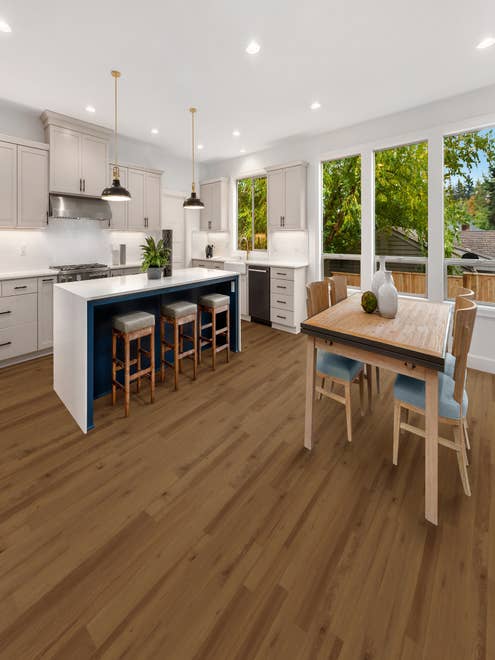 White and blue kitchen and dining room table and chairs over golden brown vinyl plank floors, with large windows overlooking outdoor deck