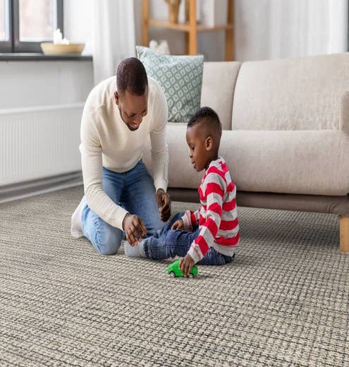 Dark skinned adult and child sitting on carpeted floor playing