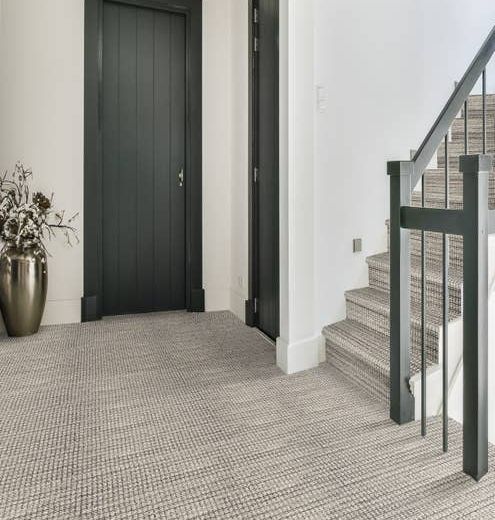 Avalon Denim carpet in shades of blue and cream at the bottom of a staircase, on the stairs in a hallway