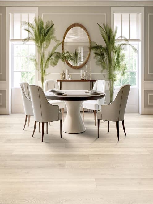 Bright and airy dining room with large windows flanking palm fronds, a large gold mirror, and a table surrounded by four modern chairs