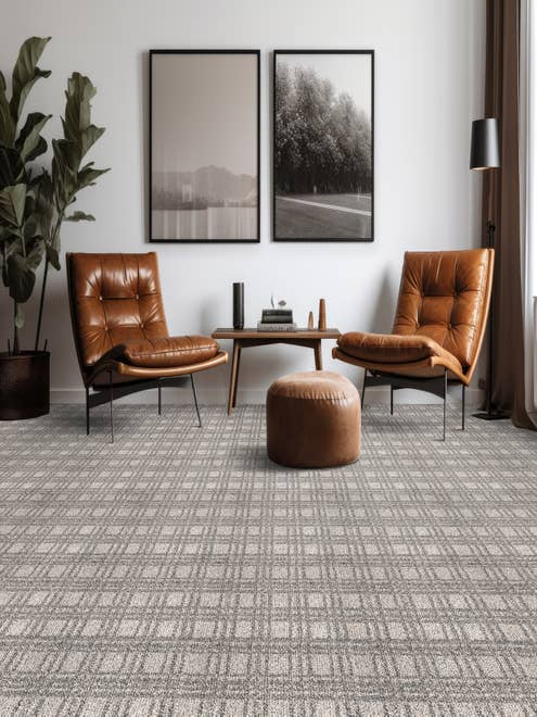 Modern home seating area with two brown leather chairs and an ottoman on a gray plaid geometric carpet