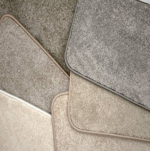 Pile of bound plush gray, tan, and cream carpet samples