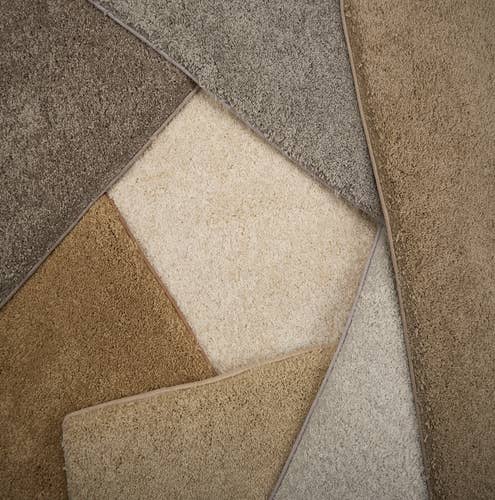 Overhead photograph of assorted plush gray, tan, and cream bound carpet samples
