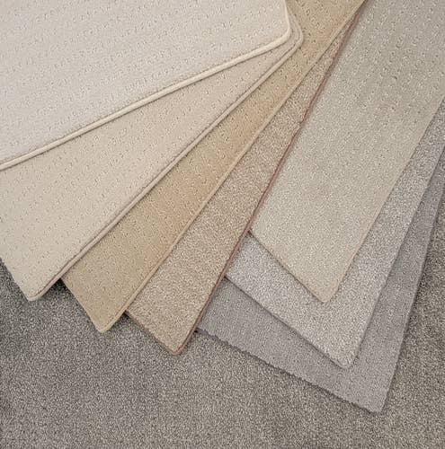 Solid textured cream, beige, and light gray carpet samples fanned out in an arc