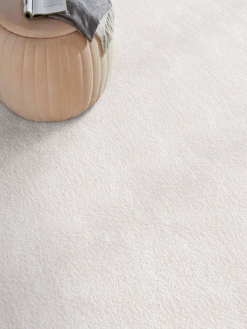 Modern tan ottoman on solid white textured carpet