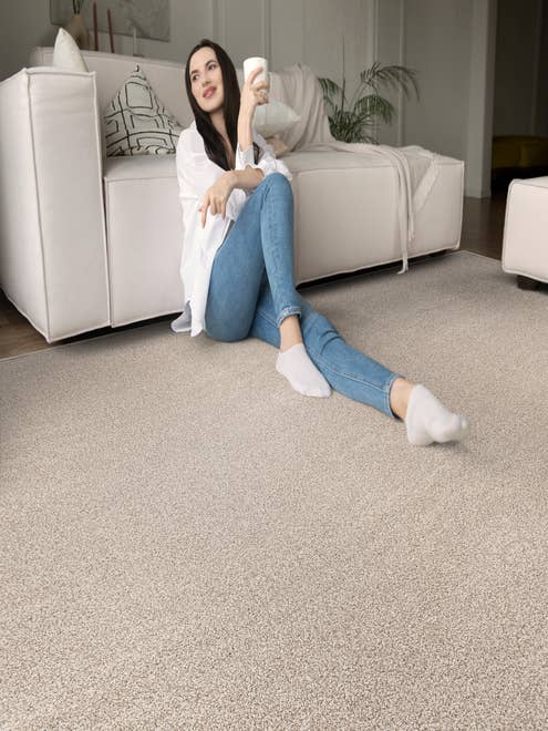 Woman leaning against white sofa on cream solid textured carpet