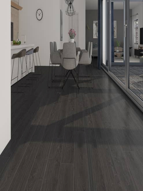 Bold, modern, black woodgrain floor leading to kitchen island, modern dining room table set, and wall of windows