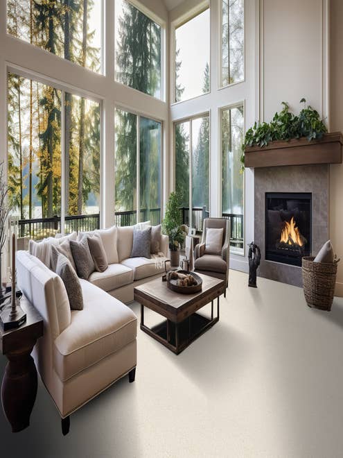 Spacious traditional living room with couch, coffee table, and fireplace set against floor to ceiling windows overlooking lakeside