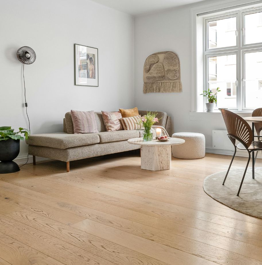 Light colored hardwood flooring in a living room with light brown couch and small white coffee table