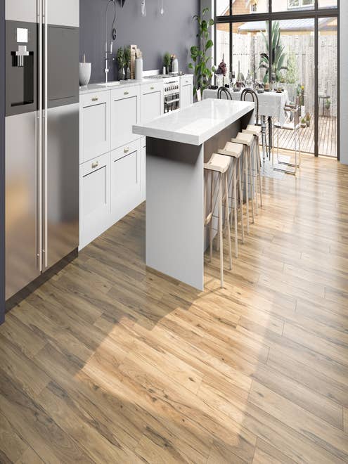 White kitchen cabinets and light gray and taupe LVP floor, with bar stools at island, with small table, and glass doors leading to deck