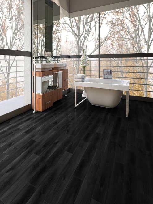 Spa space with large wooden vanity and tub facing wall of windows that show autumnal foliage outside
