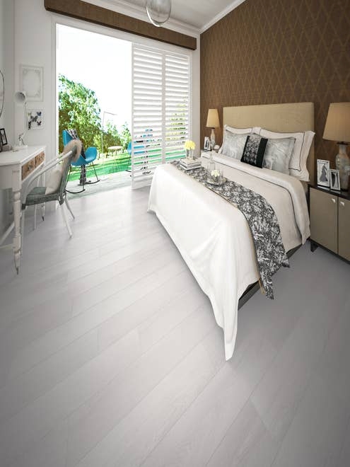 Guest bedroom with bed night stand, desk, and brown patterned wallpaper, with white-gray woodgrain LVP, with door leading to outdoor space