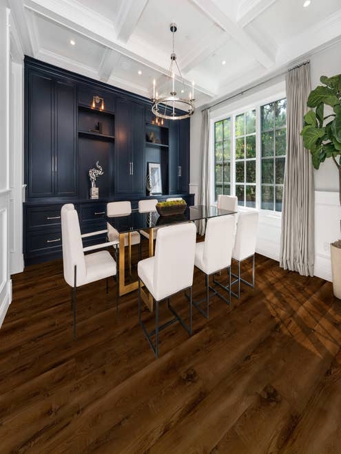 Moody dining area featuring navy built-ins, rich dark floor, large windows, and silver chandelier