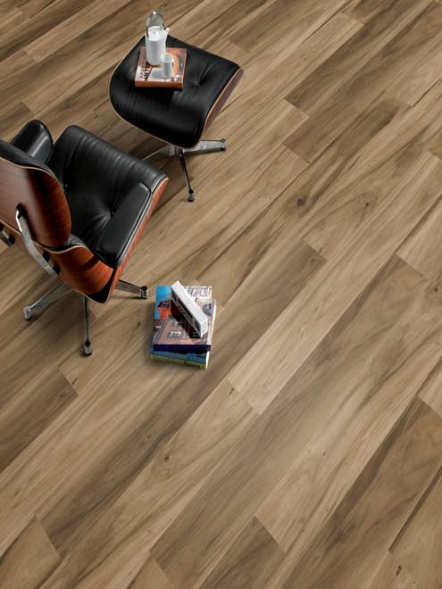 Modern leather office chair and matching ottoman beside stack of books, over Hickory Lake Teak laminate floor