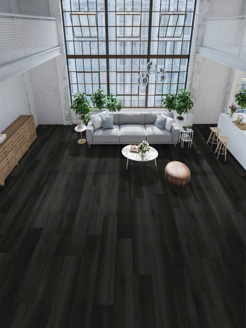 Dark, dramatic Oakdale Onyx floor in bright urban apartment with towering windows, couch, coffee table, credenza, houseplants, and kitchen island