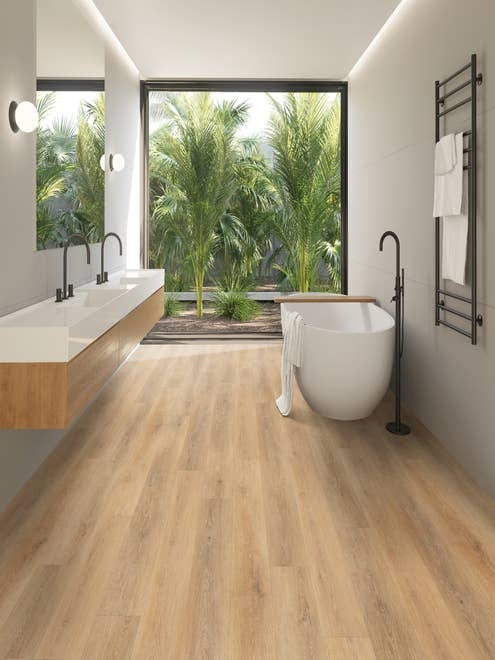 Luxury bathroom with tub and dual-sink hanging wood vanity, with view of massive window filled with fronds