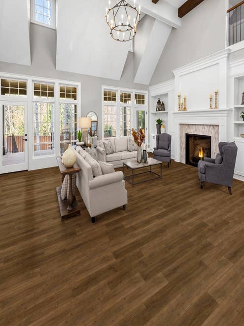 Contemporary living room with vaulted ceilings, gray walls, medium brown wood-look floor, built-in shelving, a wall of large windows, and couches and chairs before a fireplace