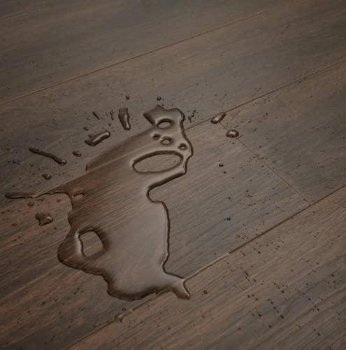 Water splash on Woodlands Walnut sample, showcasing realistic woodgrain texture and LVP's waterproof capabilities
