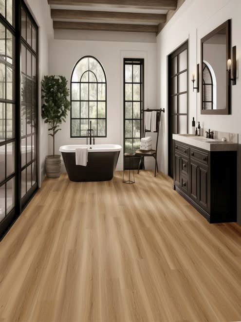 Black, white, and natural wood tone bathroom with black-framed windows, tub, vanity, mirror, and exposed wooden beam, with light brown wood-look LVP flooring