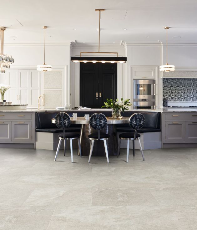 Kitchen with built-in cabinets, large black door, oversized island, multiple light fixtures, and built-in breakfast bench with table and chairs