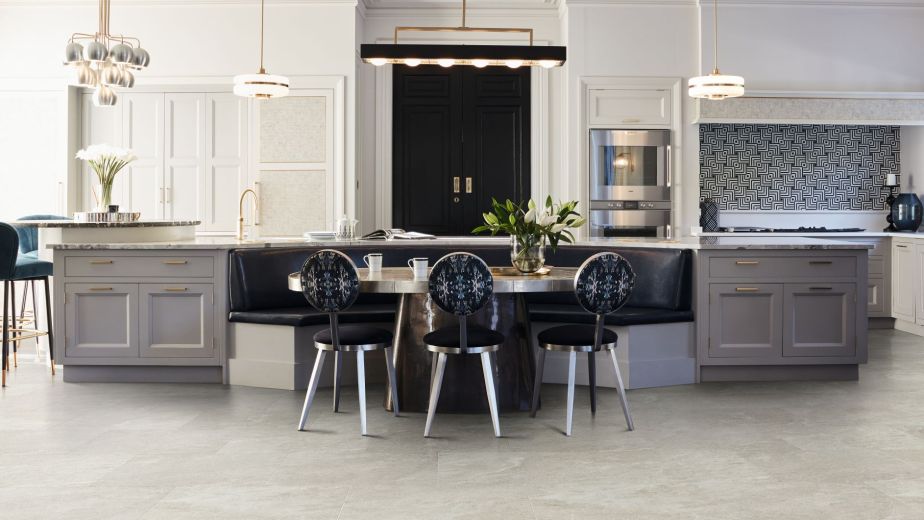 Kitchen with built-in cabinets, large black door, oversized island, multiple light fixtures, and built-in breakfast bench with table and chairs