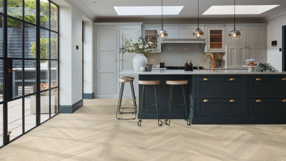 Kitchen with large bright windows, sky lights, pendant lights, built-in cabinets, and blue island with barstools over taupe/beige herringbone woodgrain floor