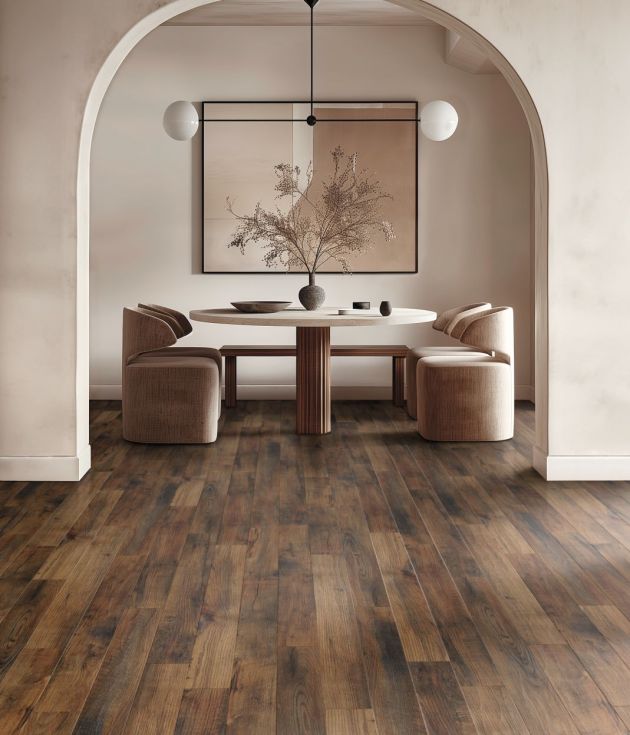 Dining area with arched doorframe, cream walls, brown woodgrain floor, and table and chairs, with large abstract painting in background and modern globe light fixture