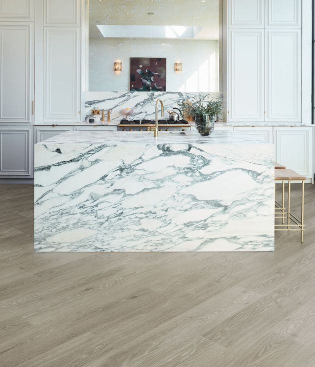 Bright airy kitchen with black-framed windows, white cabinets, marble island, with gold metal barstools, gold fixtures, and a diagonal grey woodgrain floor