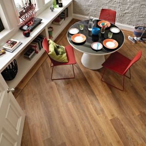 Dining area with white brick walls and copper-toned wood LVP floor installed at a diagonal, with bookshelves running under windows and table and chairs