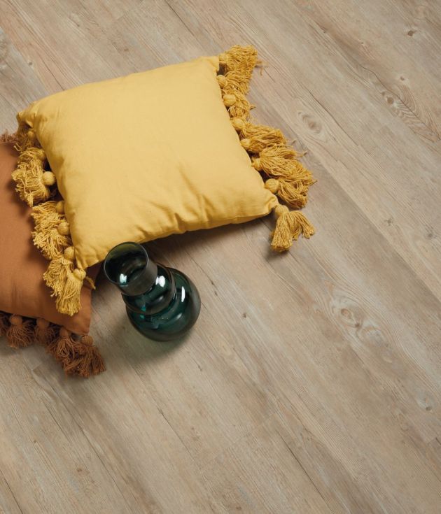 Two decorative pillows and dark glass vase on neutral woodgrain floor