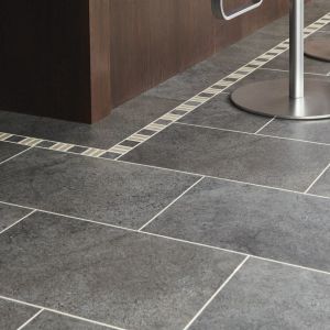 Kitchen island lined with decorative border, gray tile floor, and silver bar stool legs