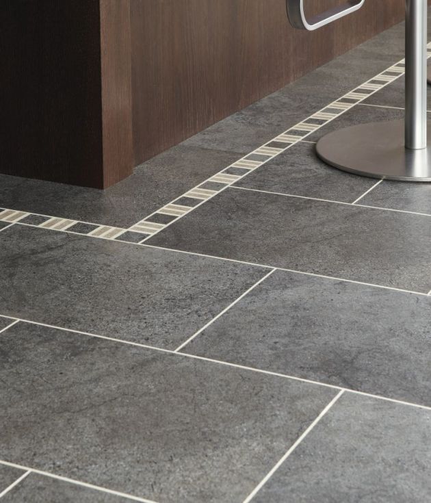 Kitchen island lined with decorative border, gray tile floor, and silver bar stool legs