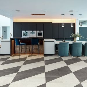 Blue kitchen cabinetry with island and attached eating area with gray and white checkered tile floor
