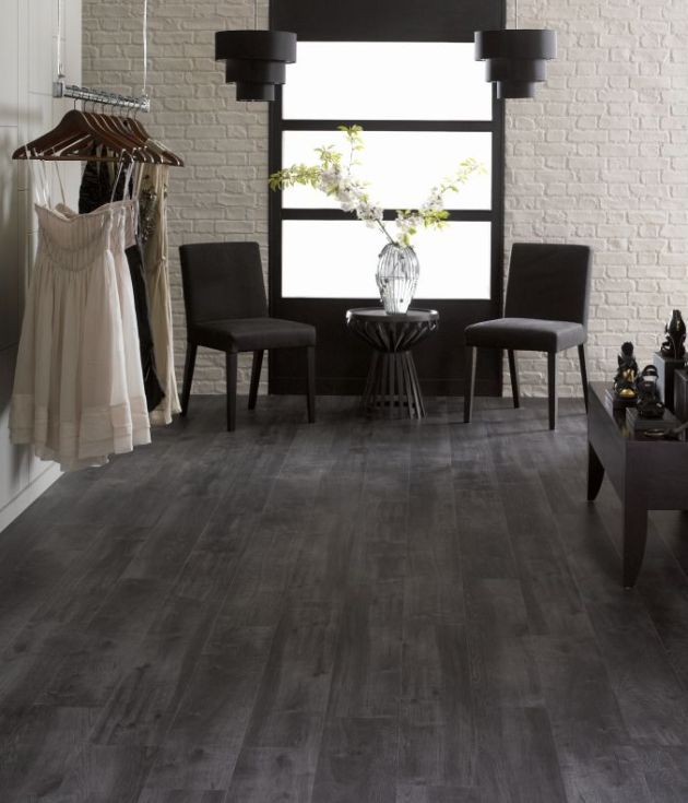 Retail space featuring black woodgrain floors, with two chairs and table stationed before frosted window, with dress rack and shoe shelving nearby