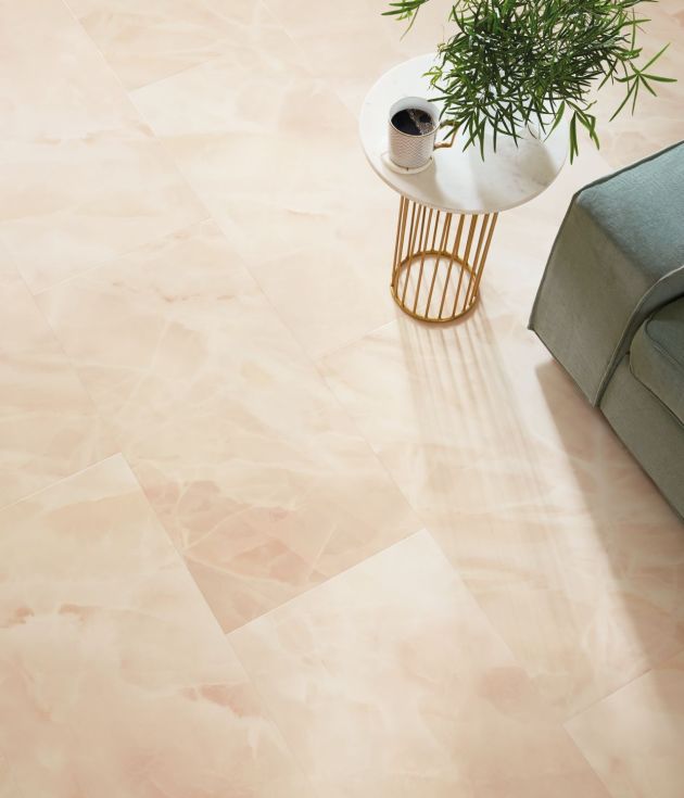 Overhead shot with sofa arm, side table, plant, and coffee cup, over pink stone-inspired tile floor