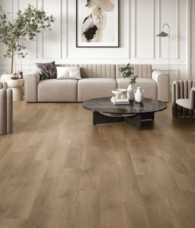 Neutral modern living space with couch, armchairs, and black marble coffee table, set in room with ecru wainscoting and muted brown woodgrain floor