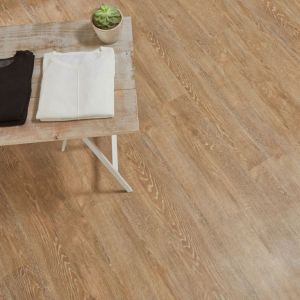 Retail space with table topped with two pairs of shiny silver shoes, two shirts, and a potted succulent in space with diagonally-installed brown reclaimed wood LVP flooring