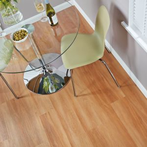 Dining space with glass table, wine bottle, and two chairs in room with gray walls and red-tinted brown woodgrain floor
