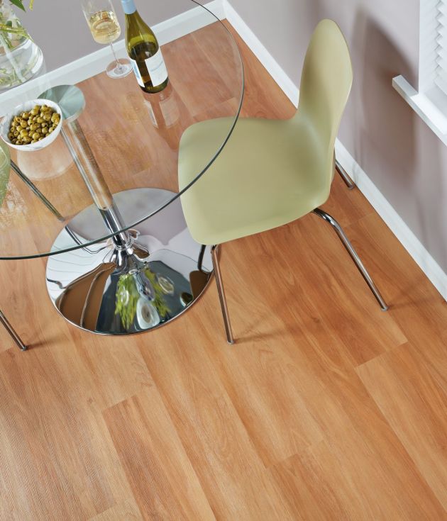 Dining space with glass table, wine bottle, and two chairs in room with gray walls and red-tinted brown woodgrain floor